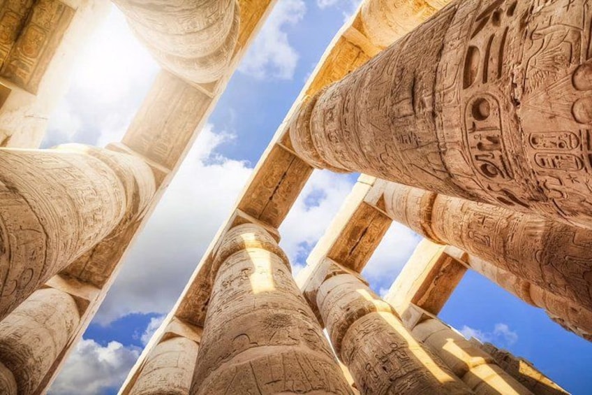 Ancient Egyptian columns with hieroglyphs, set against a clear sky. 2