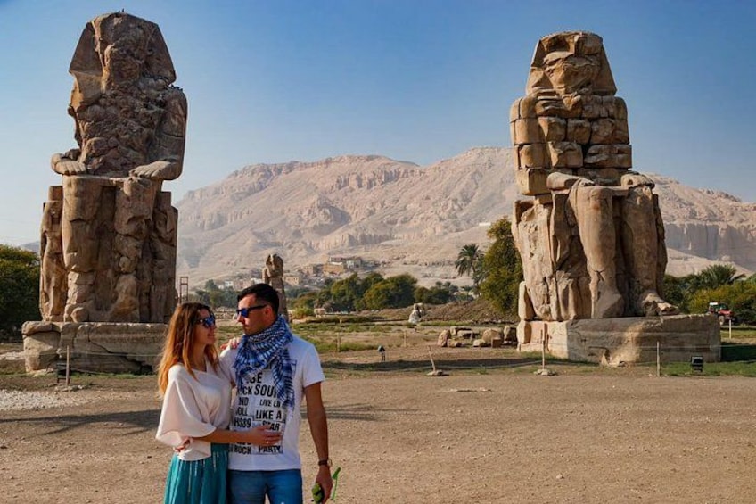 A couple standing in front of ancient Egyptian sphinx statues with desert mountains in the background. 5