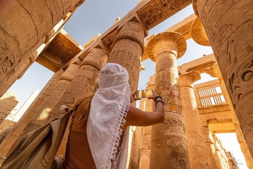 A person examining ancient Egyptian columns with hieroglyphs. 4