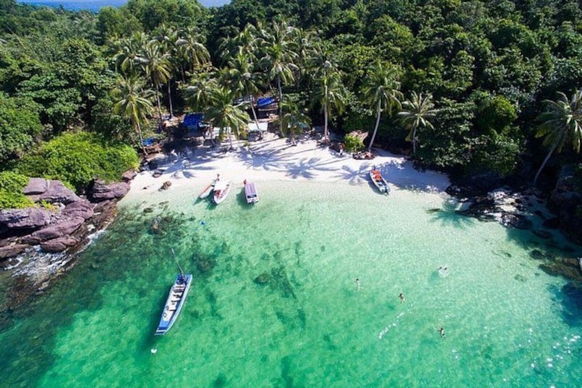 Una playa tropical con agua turquesa cristalina, palmeras y barcos. 1