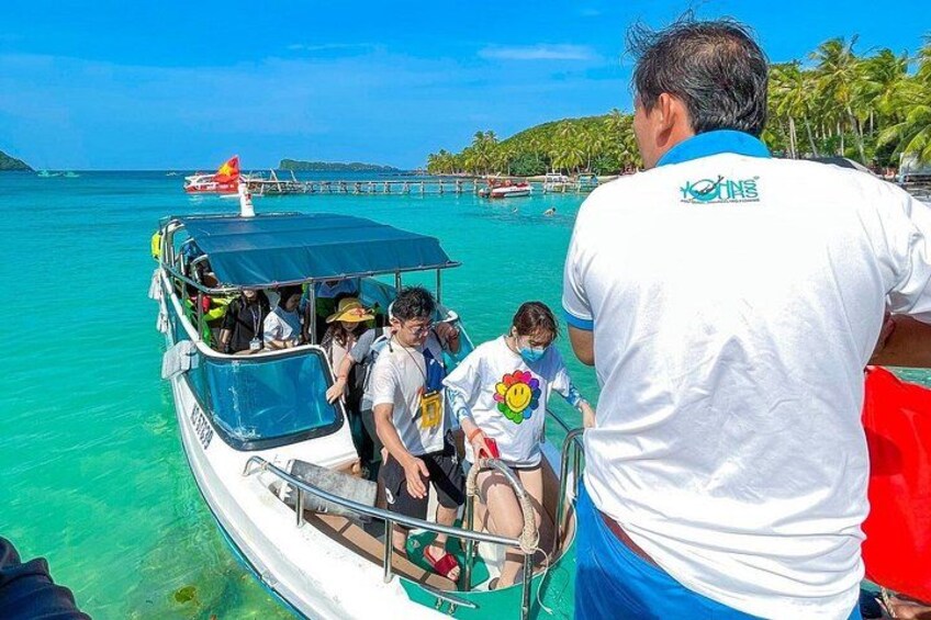 Un barco con pasajeros, un mar azul cristalino y una isla a lo lejos. 4