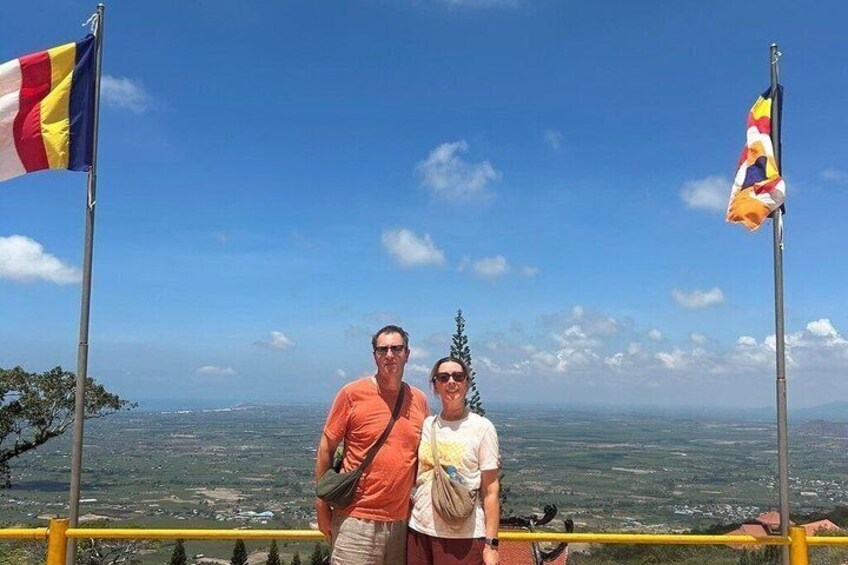 Two people standing on a viewing platform with a scenic landscape in the background. 4