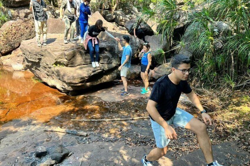 People hiking on a rocky path with a river and greenery in the background. 2
