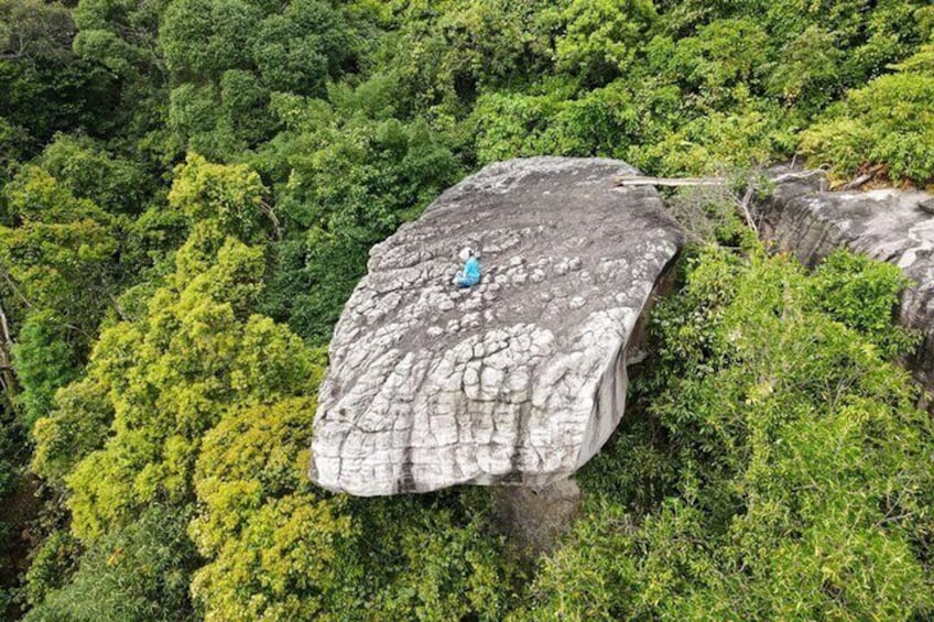 A large rock formation with a person standing on top. 5