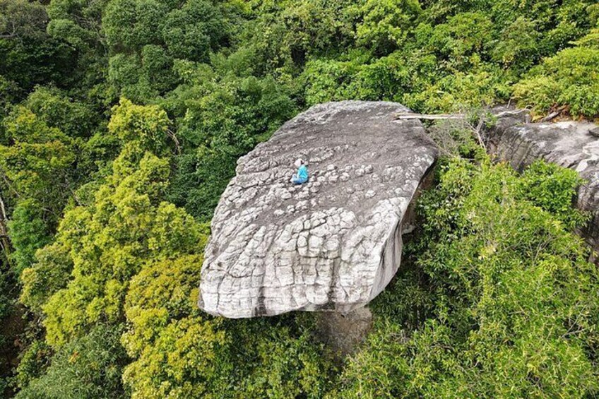 A large rock formation with a person standing on top. 5