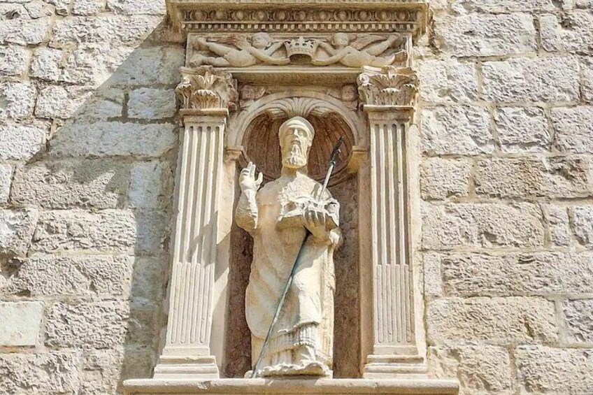 A stone statue of a figure holding a spear, set within a classical architectural niche with columns and decorative elements. 2