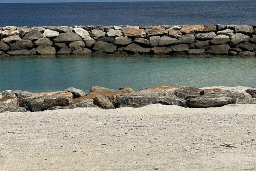 A rocky shoreline with a stone wall and calm sea. 3