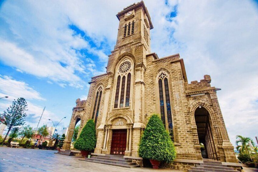 A historic church with a prominent clock tower, arched windows, and a red door. 1