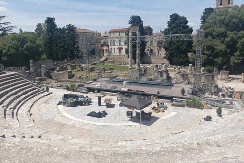 An ancient amphitheater with ruins and a modern stage setup. 5