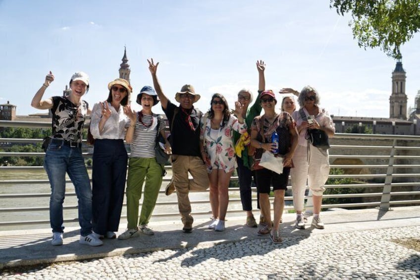 A group of people standing on a bridge with a historic building in the background. 2