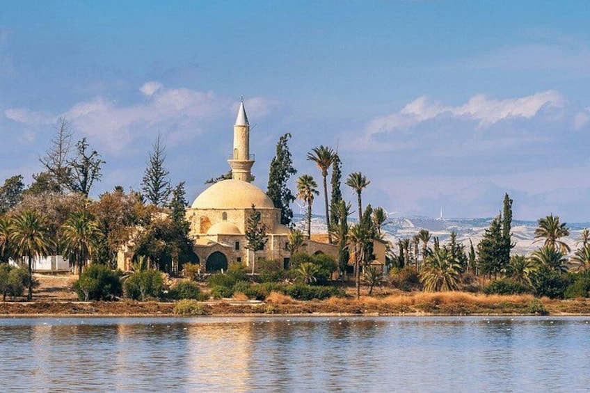 A mosque with a dome and minaret, surrounded by palm trees and a body of water. 4