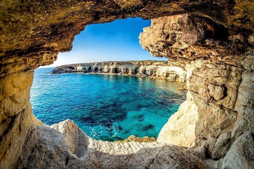 A coastal cave opening with clear blue sea and rocky cliffs. 1