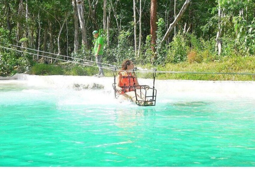 Una persona en una hamaca sobre aguas turquesas, un puente colgante y una zona boscosa. 1