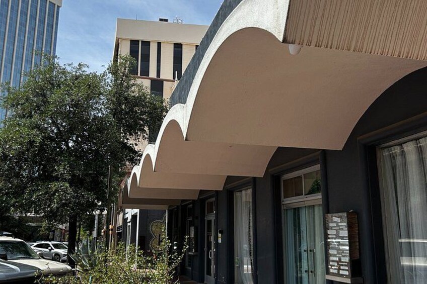 A modern building with a curved facade, parked cars, and a tree in the foreground. 5