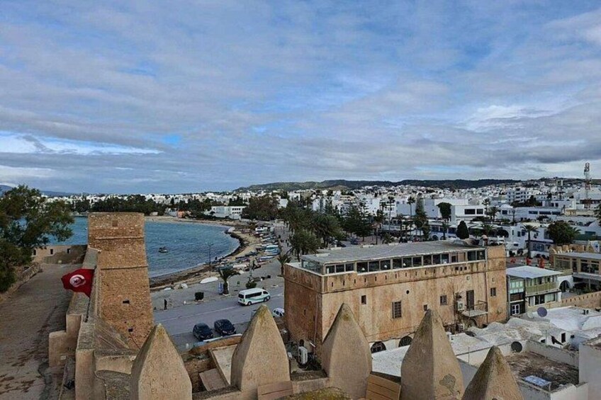 A coastal cityscape with a prominent tower, a beach, and a mix of modern and traditional architecture. 4