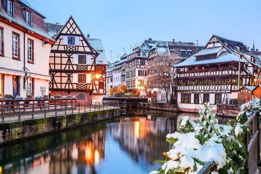 A riverside town with half-timbered houses, a bridge, and snow-covered trees. 3
