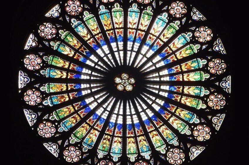 A circular stained glass window with intricate floral patterns and a central design. 5
