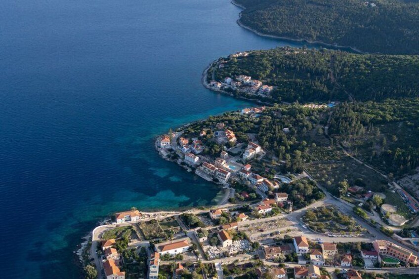 An aerial view of a coastal town with clear blue waters, a densely built-up area, and a small peninsula with buildings. 4