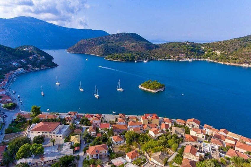 A coastal town with red-roofed buildings, a marina with sailboats, and a small island in the bay. 1