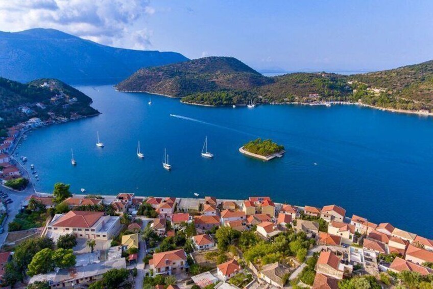 A coastal town with red-roofed buildings, a small island, and sailboats on the water. 1