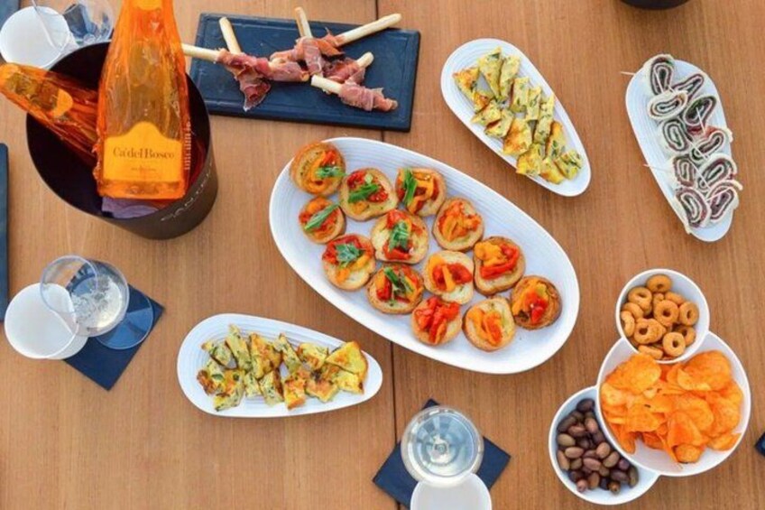 A variety of food items including appetizers, a bottle of wine, and a glass of water on a wooden table. 4