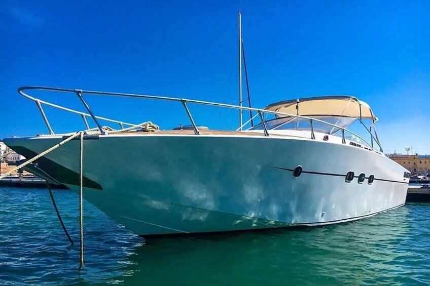 A white boat docked at a marina with clear blue water and a clear sky. 2