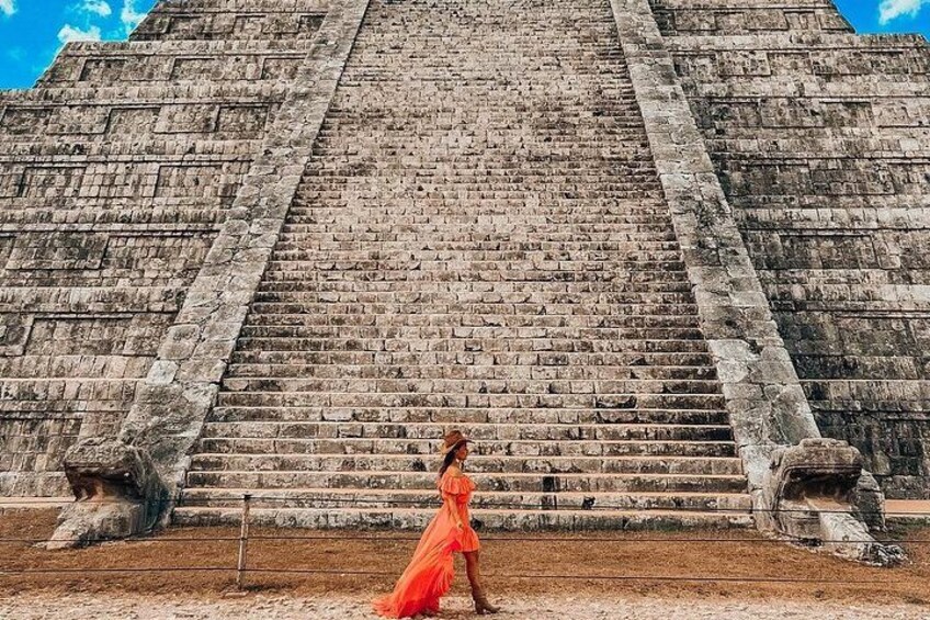 A person in a red dress walking up a large stone staircase. 5