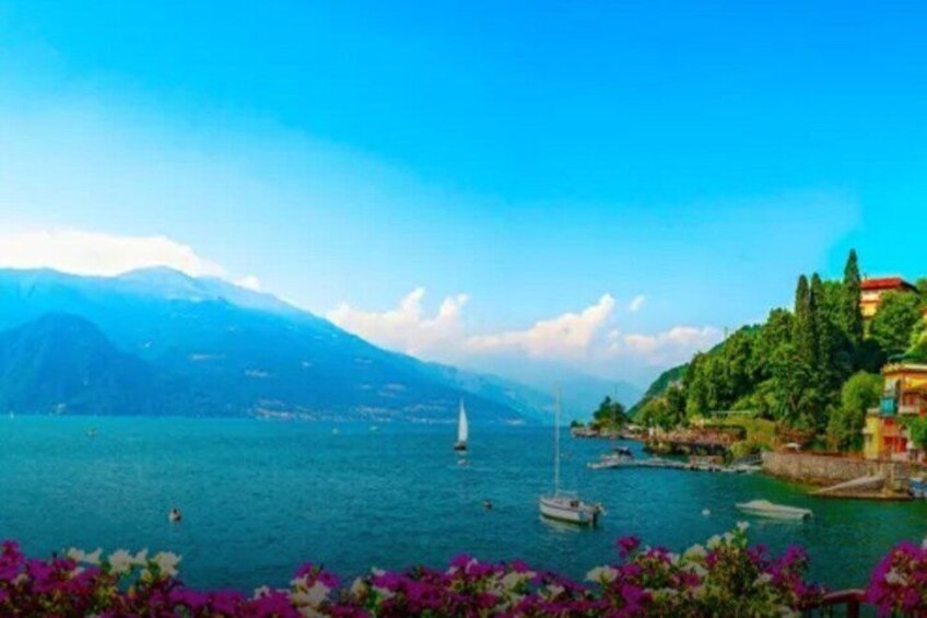 A lake with boats, a sailboat, and a mountainous backdrop. 5