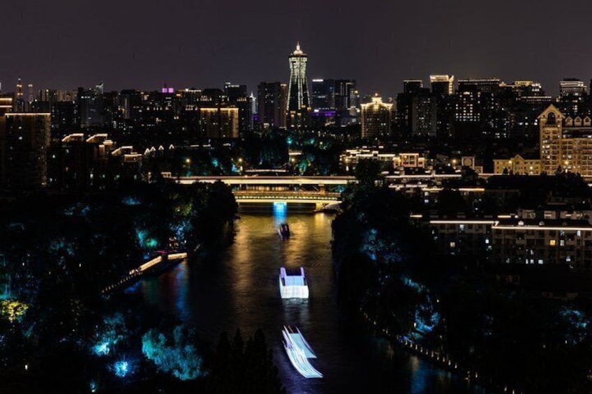 A nighttime cityscape with a prominent tower, illuminated buildings, and a river with a boat. 3