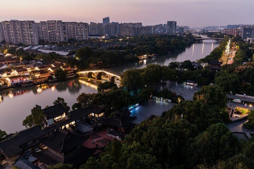 A riverside town with traditional buildings, a bridge, and modern high-rises in the background. 1