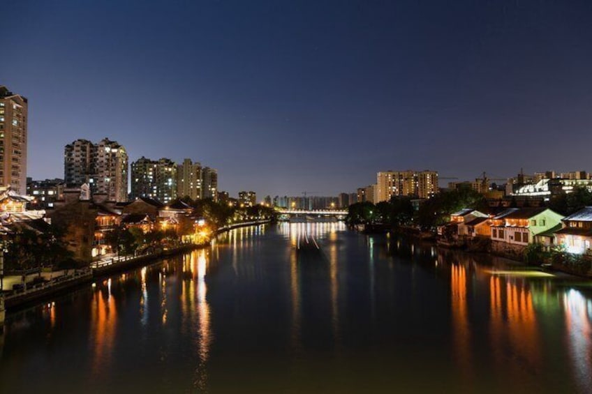 A river reflecting city lights, a bridge, and high-rise buildings at night. 4