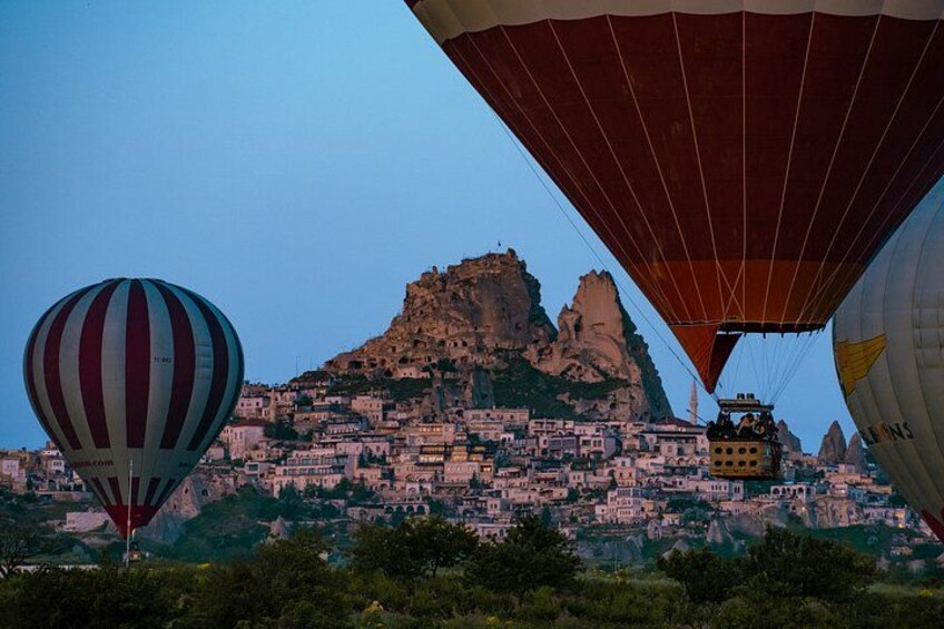 A cityscape with a prominent mountain in the background, hot air balloons, and a clear sky. 1
