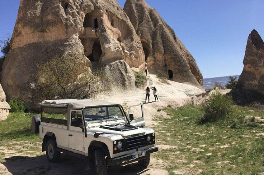 A white off-road vehicle parked in a rocky area with large rock formations and a clear sky. 5