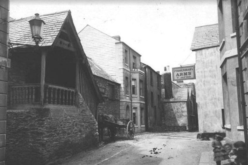A narrow street with a horse-drawn carriage, stone buildings, and a sign for 'Fletcher Arms'. 4