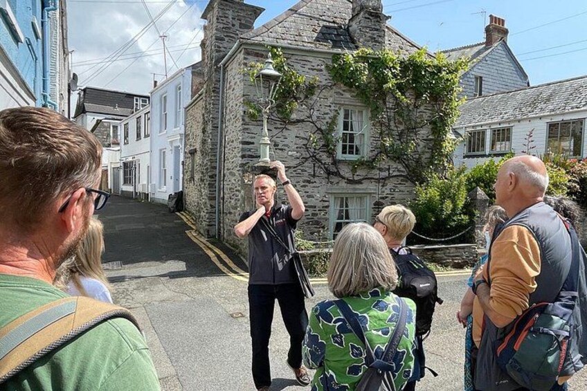 A group of people standing on a street with stone buildings and a lamp post. 5