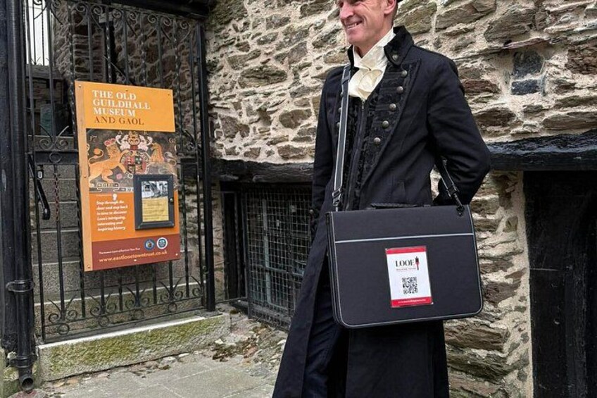 A person standing in front of a stone building with a sign for The Old Guildhall Museum and Gaol. 4