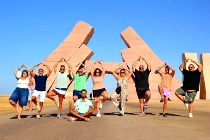 A group of people posing in front of large, abstract sculptures. 1