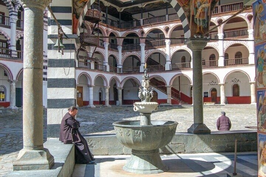 A courtyard with arches, a fountain, and a statue. 1