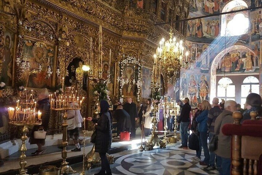 En utsmyckad kyrkinteriör med religiösa ikoner, ljuskronor och ett mönstrat golv. 2