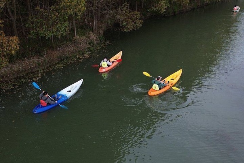 Three kayaks on a calm river surrounded by trees. 2