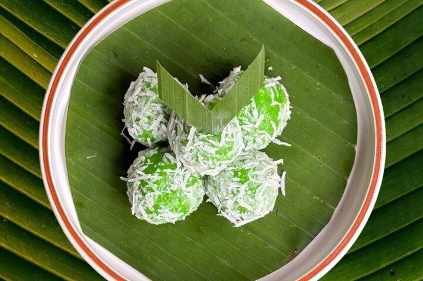 A plate of green and white coconut-covered sweets on a banana leaf. 5