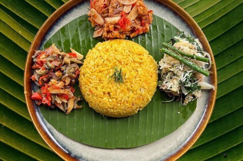A plate of food with yellow rice, vegetables, and a green leaf. 3