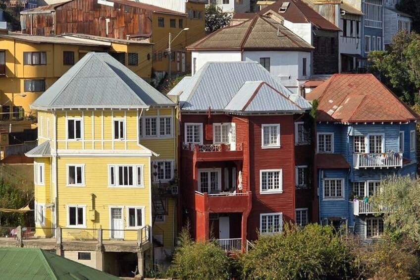 A row of colorful houses with distinct architectural styles, including a yellow house with a grey roof and a red house with a balcony. 3