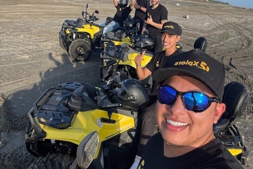 Een persoon in een gele quad, met een andere persoon op de achtergrond. 3