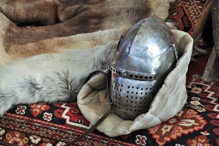 A medieval helmet in a fabric pouch on a patterned rug. 1