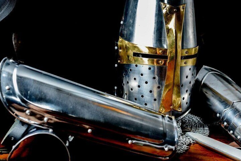 A close-up of a medieval helmet with a visor and a cylindrical object, possibly a weapon, lying beside it. 4