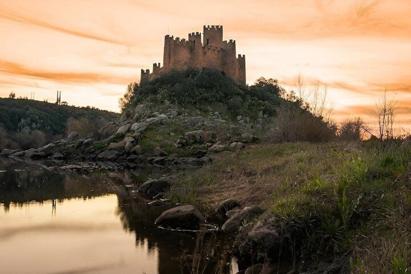 A castle on a hill with a body of water in the foreground. 2