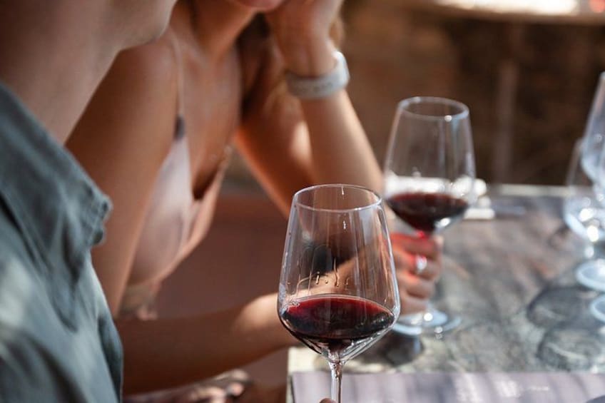 Iemand houdt een wijnglas vast aan een tafel, met nog een glas te zien. 4