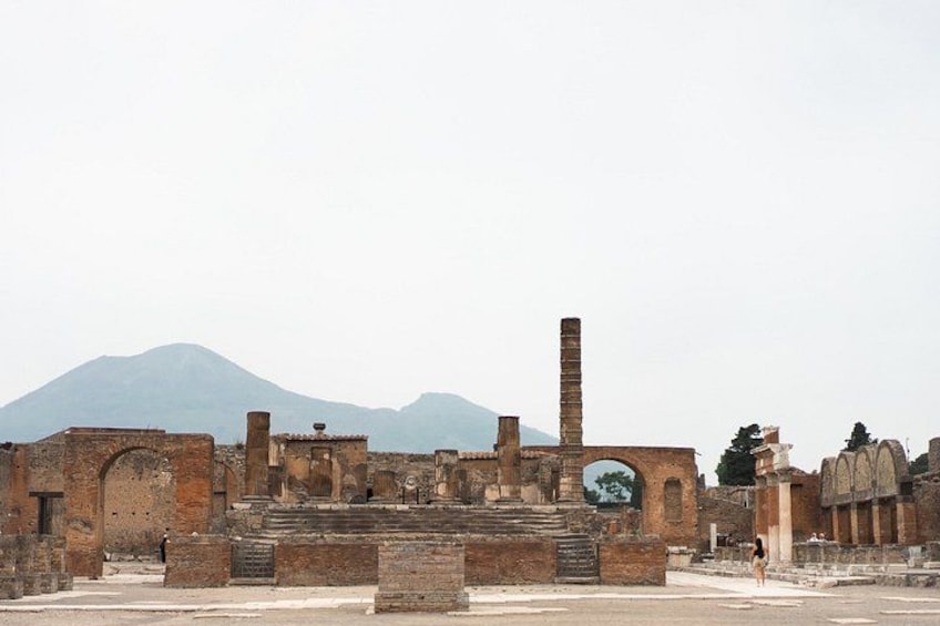Ancient ruins with a brick chimney, arched doorways, and a mountain in the background. 3