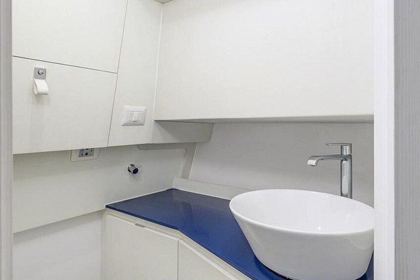 A bathroom with a white sink, blue countertop, and white cabinets. 2